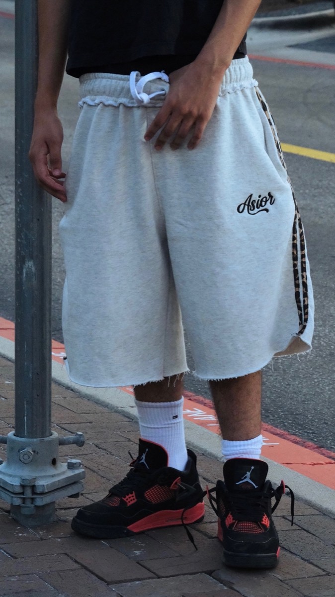 Light Asior shorts worn with white socks and sneakers on a kerb