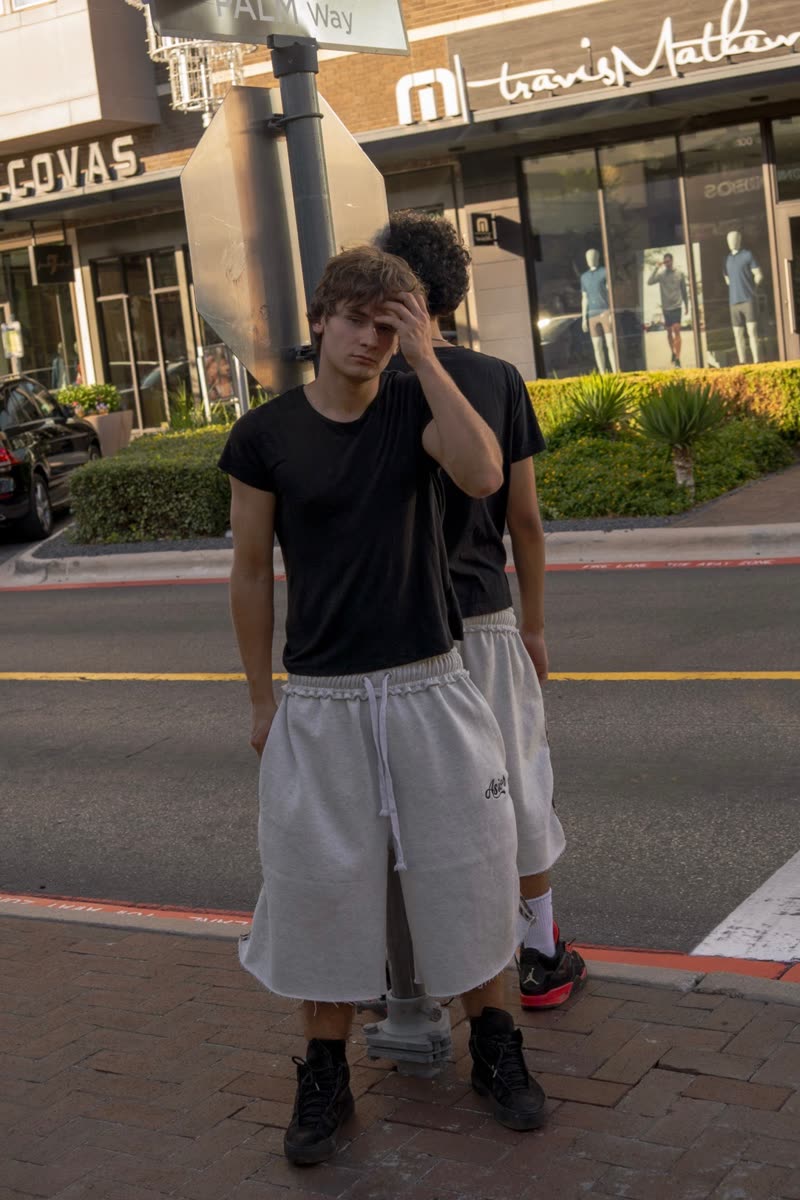 Two models crossing a street in black tees and light shorts