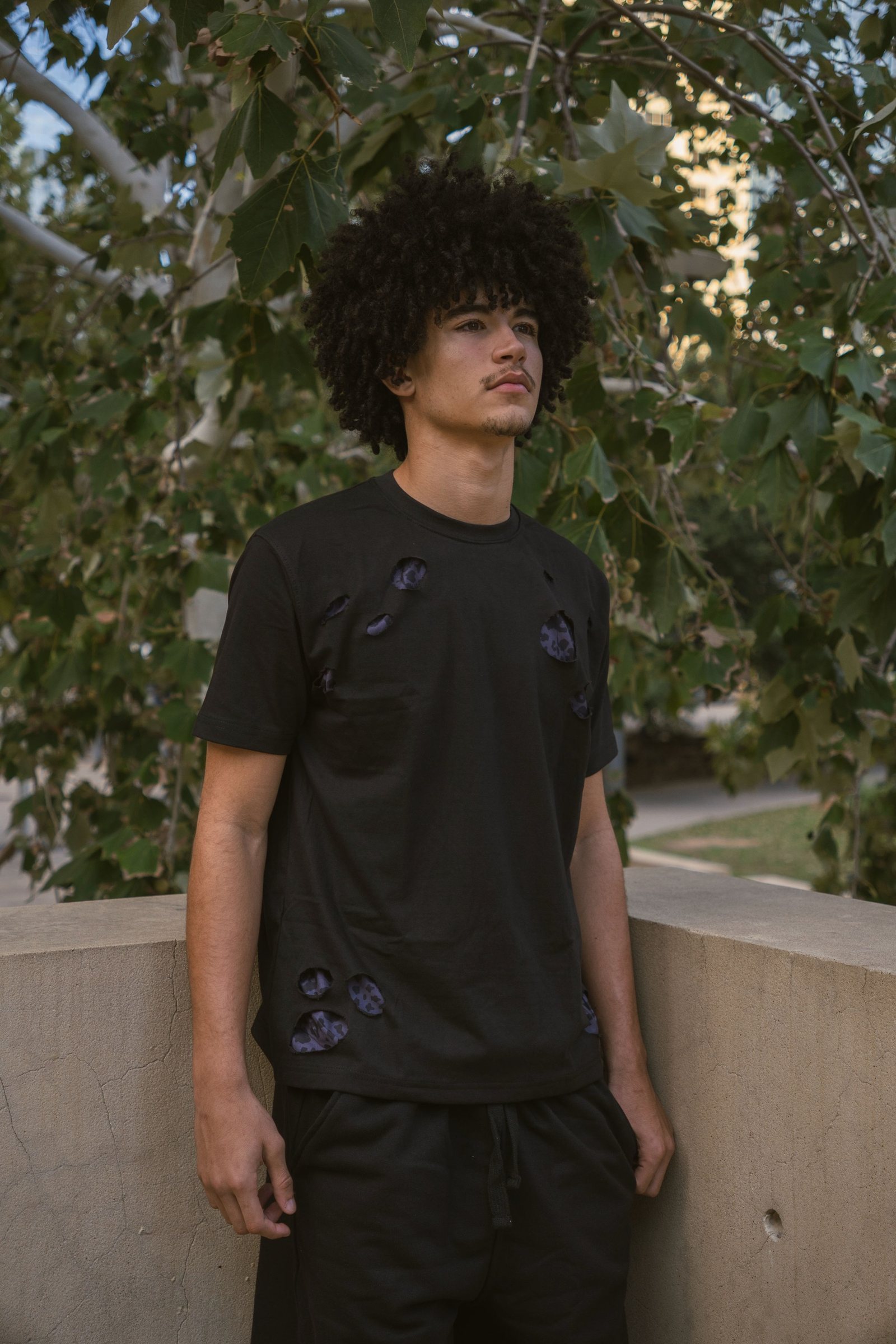 Model in the Holes Tee under a tree, the leopard backing showing through