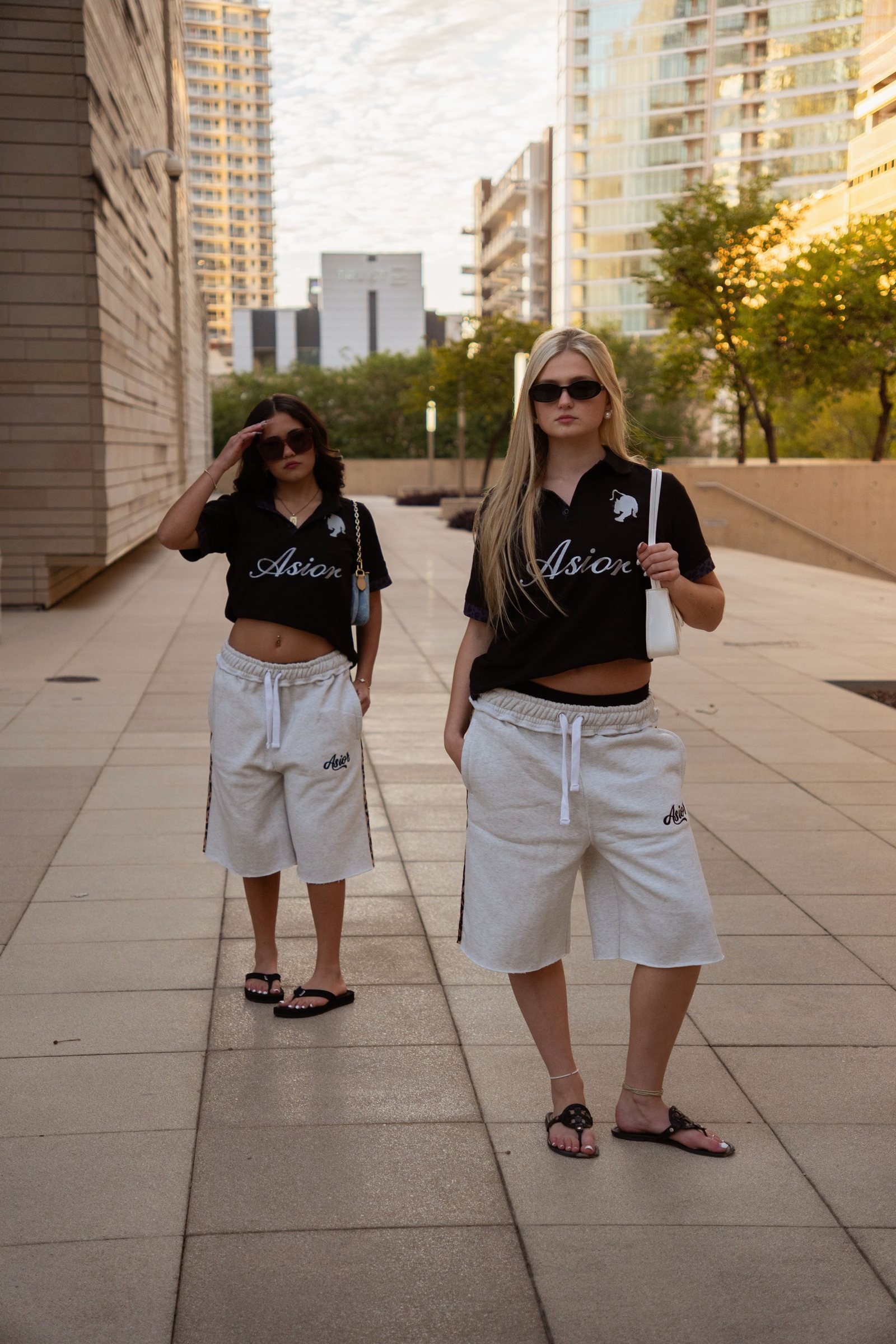 Two models in Asior polos and sweat shorts walking a downtown passage